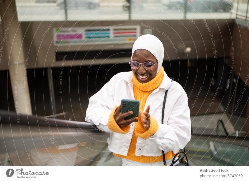 Smiling woman using smartphone in urban setting female city technology communication smiling happy joy street outdoor fashion style modern casual hijab islam