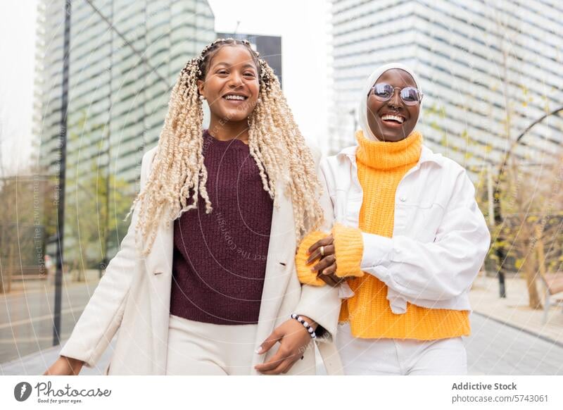Two joyful black women enjoying time together in urban setting woman female city friendship cheerful glasses high-rise stroll pair background enjoyment
