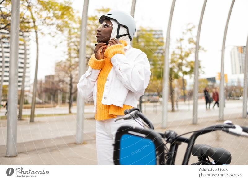 Black woman adjusting helmet near bike in city female black urban bicycle electric hijab safety fashion lifestyle outdoor park autumn transportation