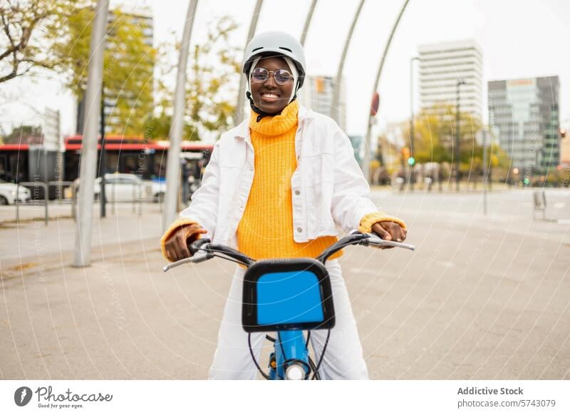 Smiling African woman cycling in cityscape female urban bike ride helmet glasses cheerful skyscraper outdoor smile transportation leisure lifestyle sporty