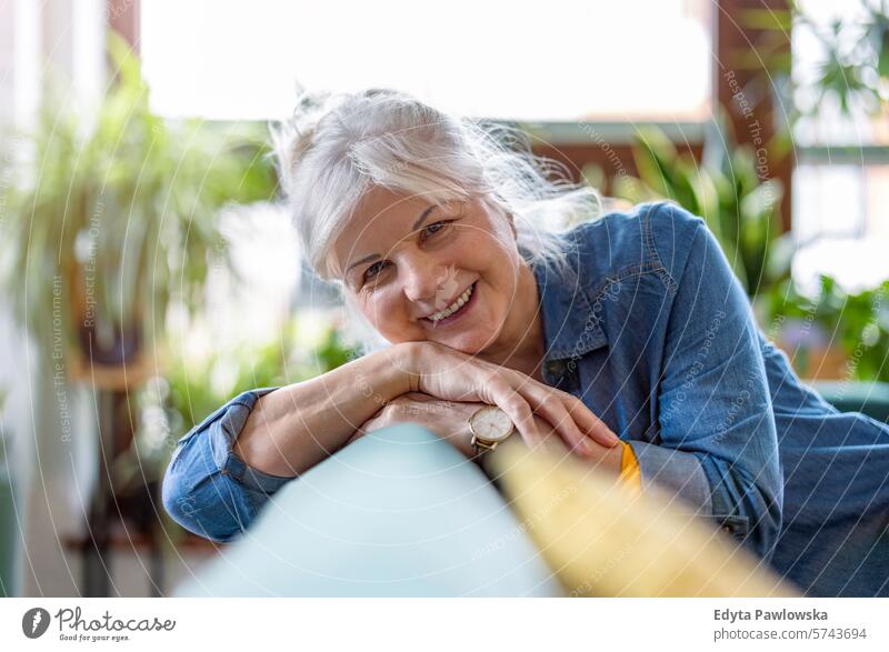 Mature woman looking at camera and smiling in her living room at home people casual day portrait indoors real people white people adult mature retired old