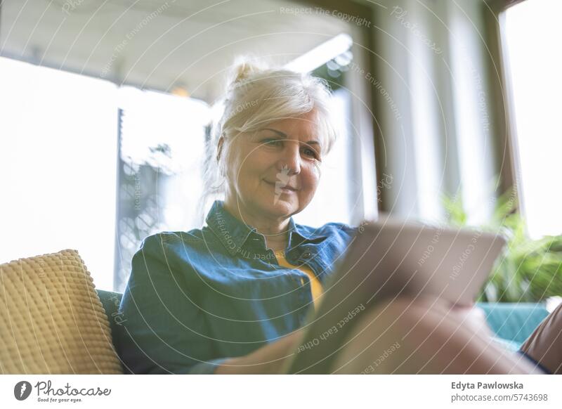 Mature woman using digital tablet while sitting on sofa at home people casual day portrait indoors real people white people adult mature retired old one person