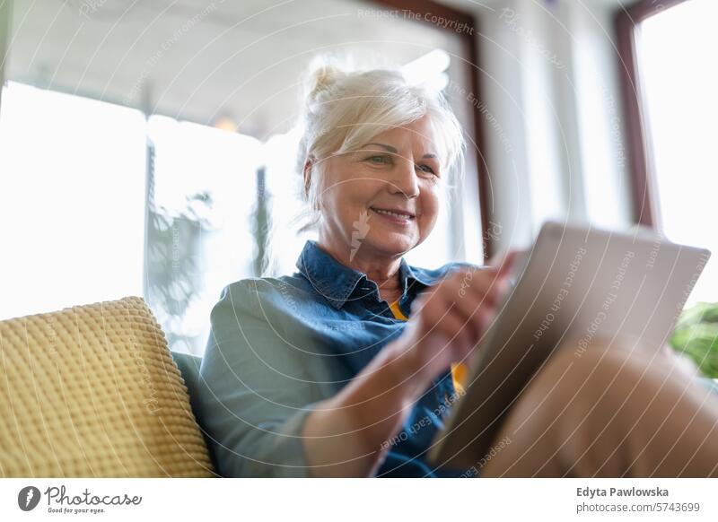 Mature woman using digital tablet while sitting on sofa at home people casual day portrait indoors real people white people adult mature retired old one person