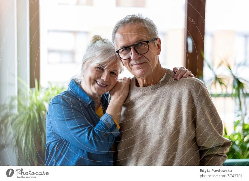 Portrait of happy senior couple embracing each other in living room at home people caucasian grey hair casual day portrait indoors real people white people