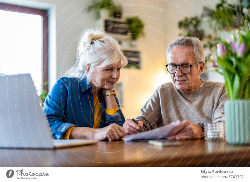 Senior couple sitting at the table discussing home finances people caucasian grey hair casual day portrait indoors real people white people adult mature retired