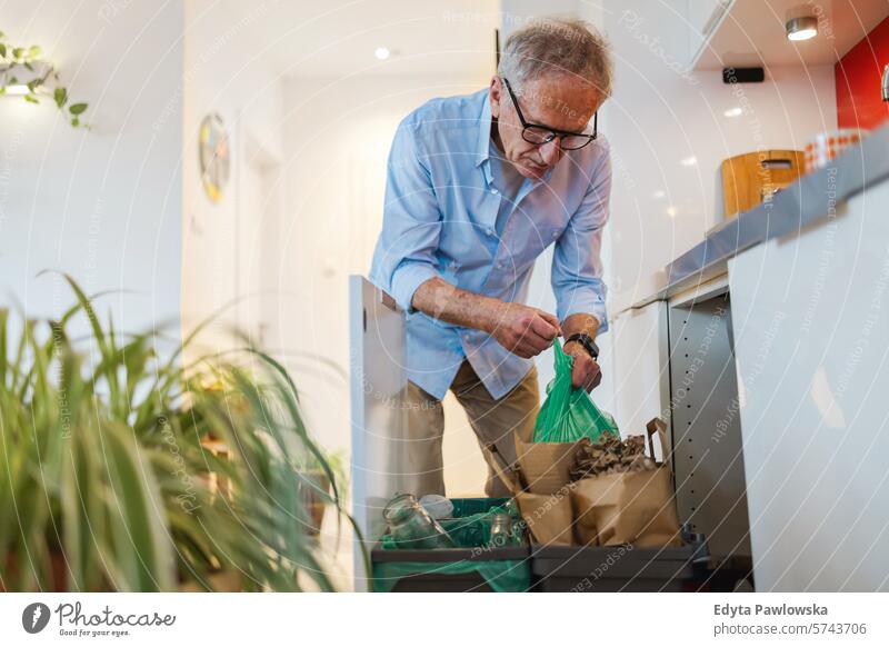 Senior man sorting garbage in recycling bins at home people caucasian grey hair casual day portrait indoors real people white people adult mature retired old
