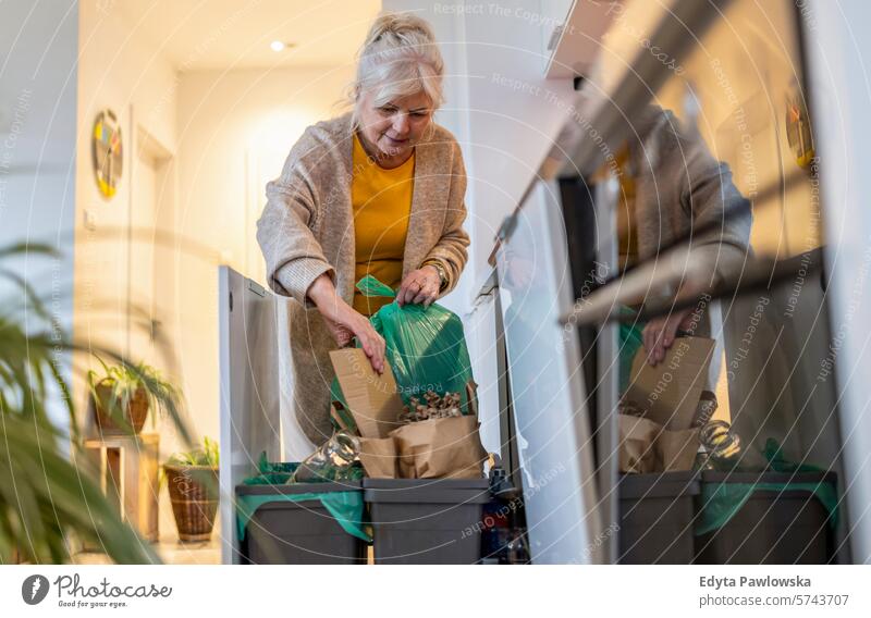 Senior woman sorting garbage in recycling bins at home people casual day portrait indoors real people white people adult mature retired old one person lifestyle