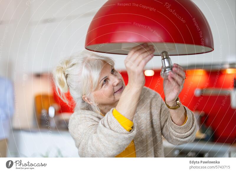 Senior woman changing light bulb in her home people casual day portrait indoors real people white people adult mature retired old one person lifestyle senior
