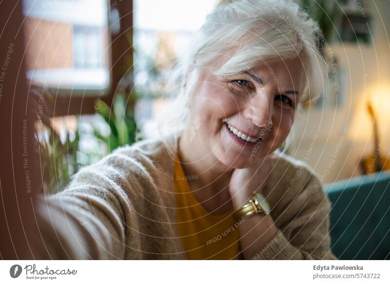 Portrait of smiling senior woman taking selfie at home people casual day portrait indoors real people white people adult mature retired old one person lifestyle