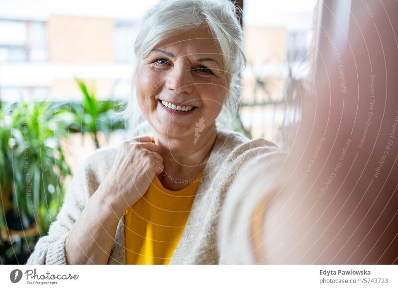 Portrait of smiling senior woman taking selfie at home people casual day portrait indoors real people white people adult mature retired old one person lifestyle