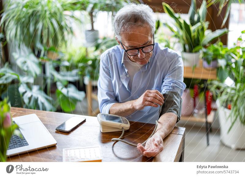 Senior man measuring blood pressure at home people caucasian grey hair casual day portrait indoors real people white people adult mature retired old one person