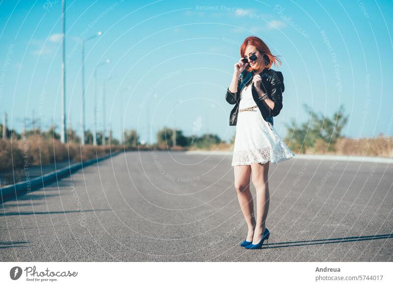 red-haired girl in a black jacket and blue glasses blue eyes bracelet dress happiness joy leather light portrait road rock summer walk white young