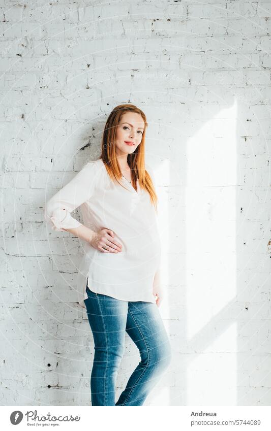 red-haired pregnant girl in a light blouse and blue jeans beautiful birth bright chair child day diversity family fpchallengediversity hairstyle inside love