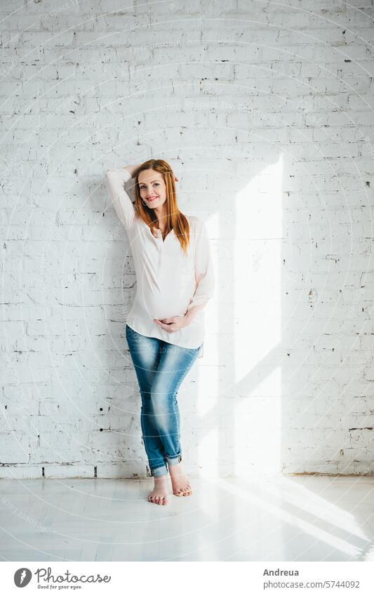 red-haired pregnant girl in a light blouse and blue jeans beautiful birth bright chair child day diversity family fpchallengediversity hairstyle inside love