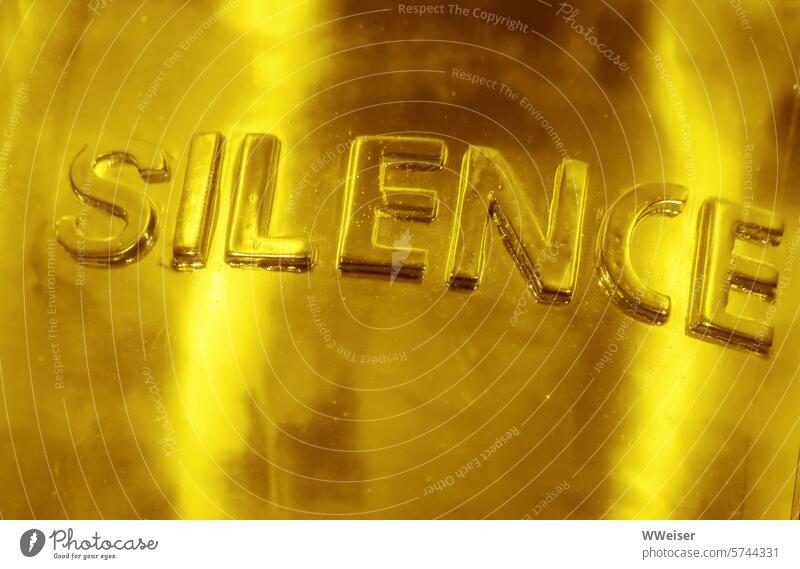 The lettering on a noble background suggests: Silence is golden To be silent Proverb Gold writing message embassy Hint discreet keep one's mouth shut Restraint