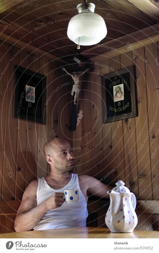 A man is sitting in a mountain hut. He is holding a cup in his hand. There is a pot on the table. Drinking Coffee Relaxation Calm Lamp Young man