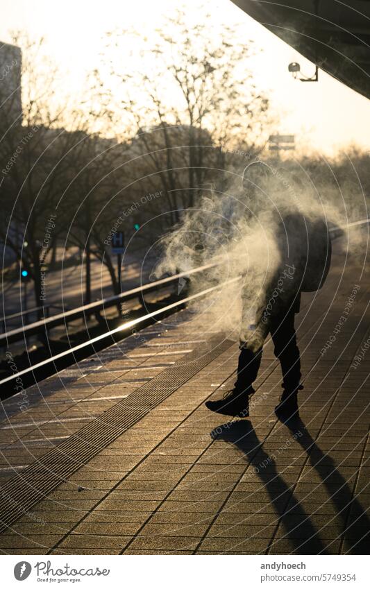 A smoking passenger on the platform at sunrise arrival cigarette city cold dangerous departure european forbidden health illegal information infrastructure