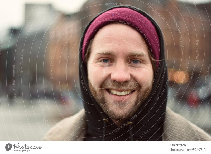 HAPPY - LAUGHING - IN THE MIDDLE OF IT ALL Man 30 - 40 years Facial hair Blonde Cap Hooded sweater cheerful Laughter fortunate contented City life In transit