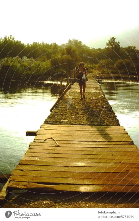 Frau wandert auf einem Holzsteg wandern Fluß exotisch Steg Abendstimmung Sommer reise urlaub Landschaft Natur pilgern Pilgerin junge frau ferien globetrotter