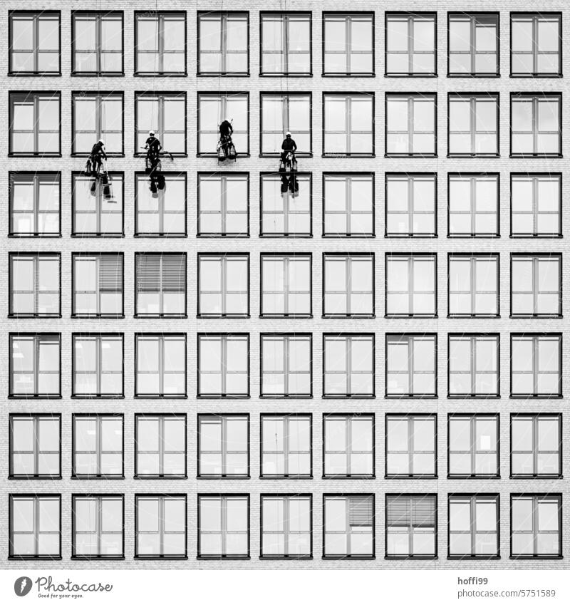 Window cleaner on a rope in front of the monotonous glass facade of a high-rise office building Window cleaning urban Climbing facade climber Rope team Cleaning