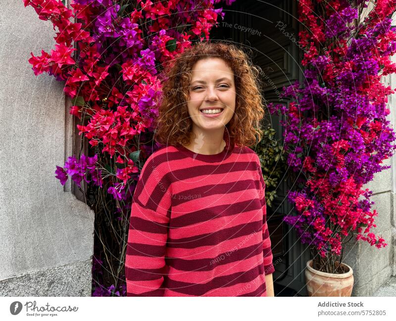 Curly-haired redhead woman smiling in a colorful city garden portrait smile curly hair floral arch vibrant urban happy cheerful pink flowers bougainvillea