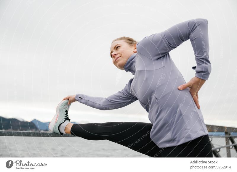 Young woman stretching before exercise outdoors fitness athlete workout cloudy day water backdrop preparation routine health active lifestyle wellness