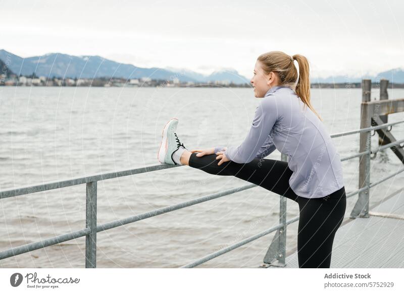 Waterfront Leg Stretch with Scenic Mountain View woman stretching leg railing waterfront mountain background fitness exercise outdoor wellness athletic health