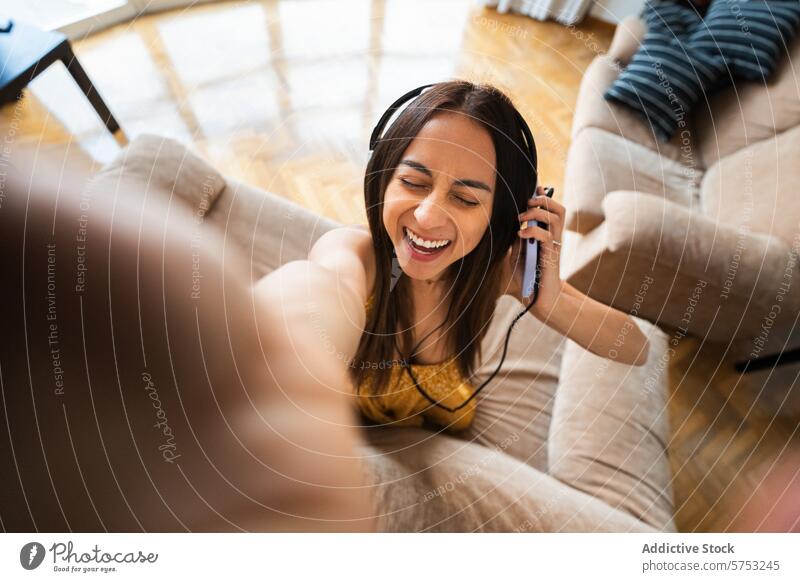 Happy young woman taking a selfie with headphones latin woman latina smile home cheerful interior leisure lifestyle happy casual photography relaxation music