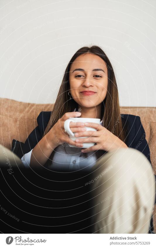 Smiling businesswoman enjoying a coffee break smiling mug couch content young professional relax comfort corporate office casual employee break time happiness