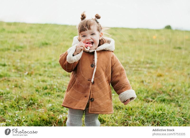 Joyful Toddler Girl in Coat Playing Outdoors in Field child toddler girl outdoor field play smile cheerful cute coat warm autumn nature lifestyle casual