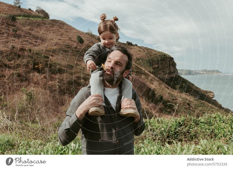 Tender moment with father carrying daughter on shoulders family love bonding outdoor nature landscape sea shoulder ride child parent quality time happiness