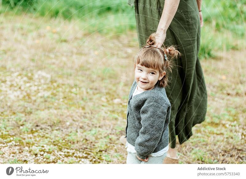 Joyful child holding hands with adult in nature smile happy grassy field care connection girl joy outdoor playful bonding family guardian love cheerful