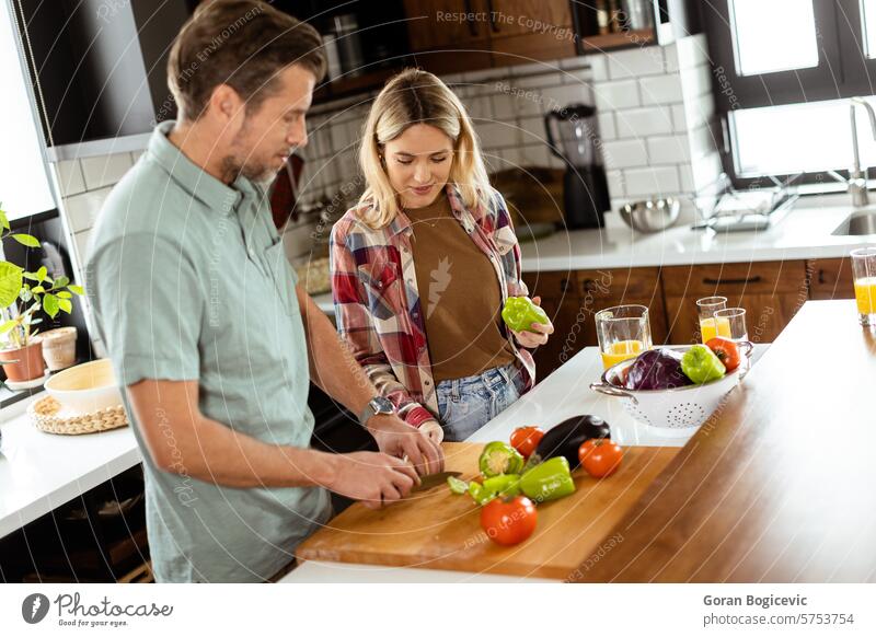 Smiling man and woman chopping fresh vegetables on a kitchen island, enjoying a healthy cooking activity together bell peppers bonding bright brunch