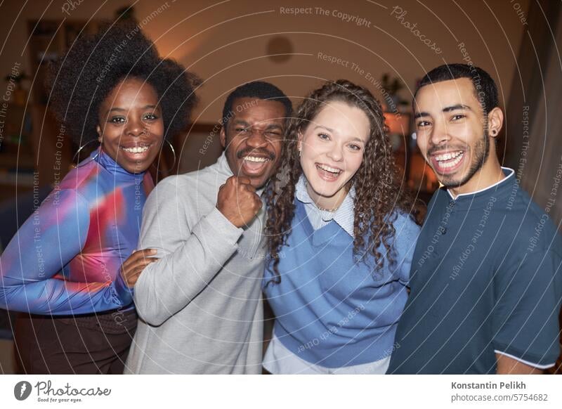 Diverse group of cheerful adult friends looking at camera and smiling during house party shot with flash home people diversity multiethnic look at camera