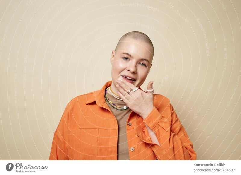 Portrait of confident bald young woman wearing bright orange jacket in studio female girl gen Z hair loss alopecia mouth lips lick cancer chemotherapy beauty