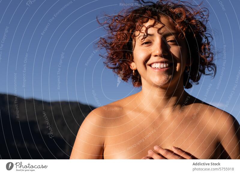 Joyful contemporary dancer basking in sunlight smile joy sunshine warmth woman curly hair blue sky cheerful portrait bright day happiness expressive performer