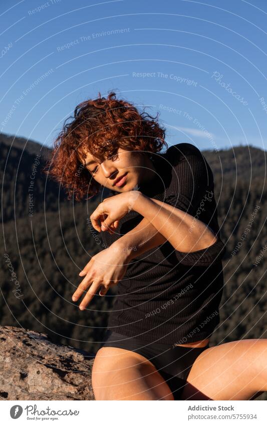 Contemporary dancer in natural outdoor setting contemporary mountain sunlight poised elegant expression contemplative scenic glow warmth rock female performance