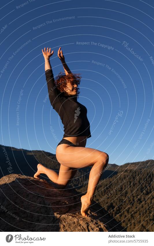 Graceful dancer posing on a mountain at dusk contemporary pose freedom expression young grace blue sky outdoor female artistic fitness flexibility movement