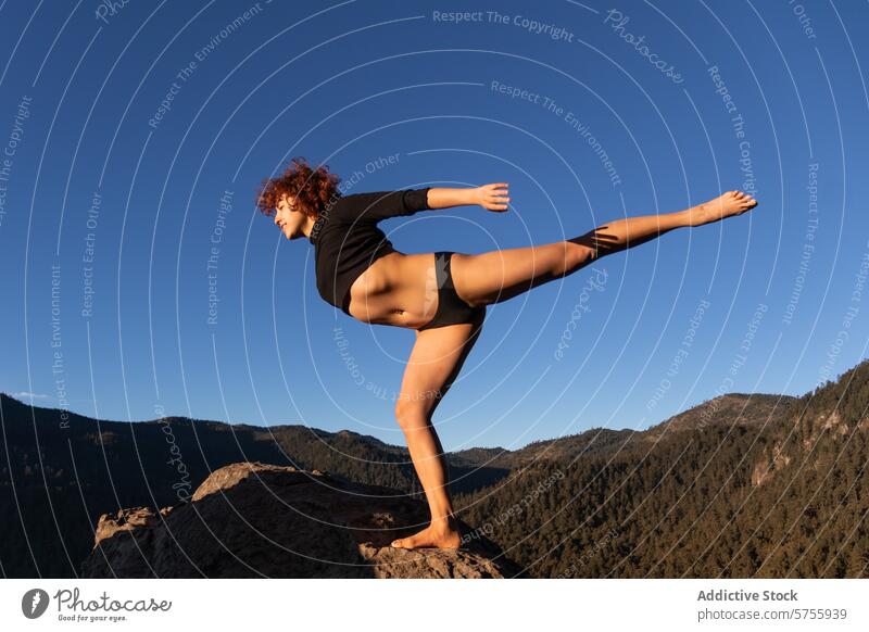 Graceful contemporary dancer performing outdoor pose mountain rock blue sky grace elegance performance skill art culture female focused expressive freedom