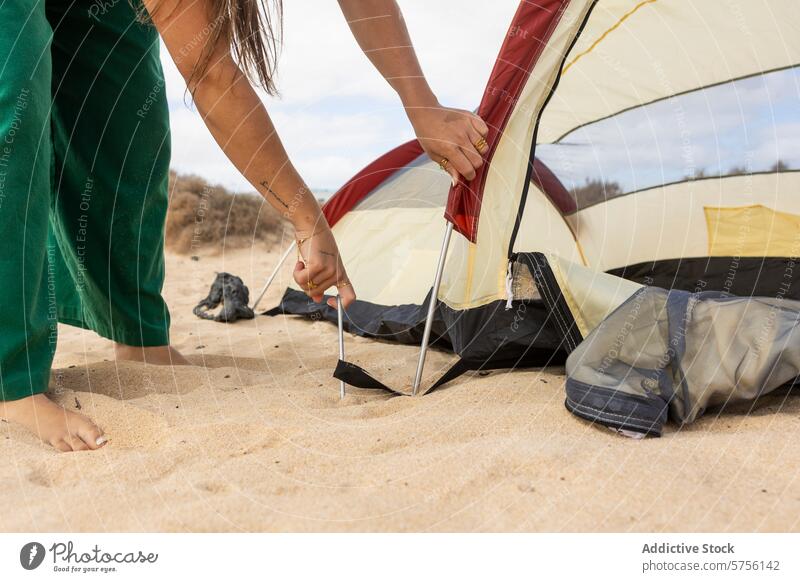 Close-up of anonymous woman pitching a tent on a beach, capturing the essence of outdoor adventure and teamwork camping setup sandy travel holiday vacation
