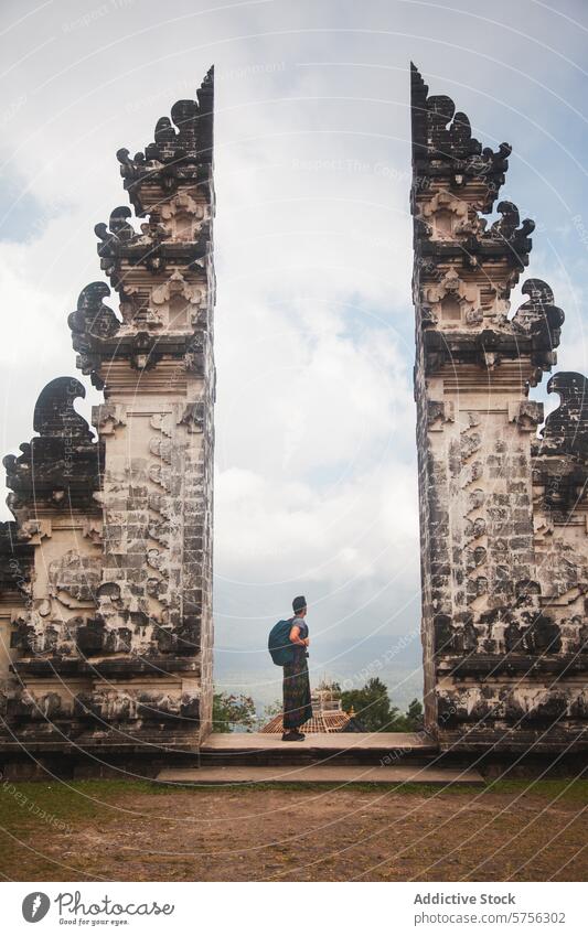 Traveler embracing culture at iconic Balinese gate indonesia bali traveler candi bentar traditional entrance sacred attire experience temple architecture