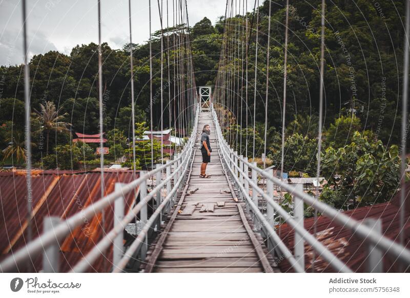 Exploring a serene suspension bridge in Indonesia traveler indonesia wooden greenery tranquil village exploration walking nature outdoor adventure forest