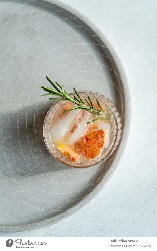 Top view of crafted vodka tonic cocktail adorned with grapefruit and rosemary, resting on a textured tray for an upscale serving experience drink beverage ice