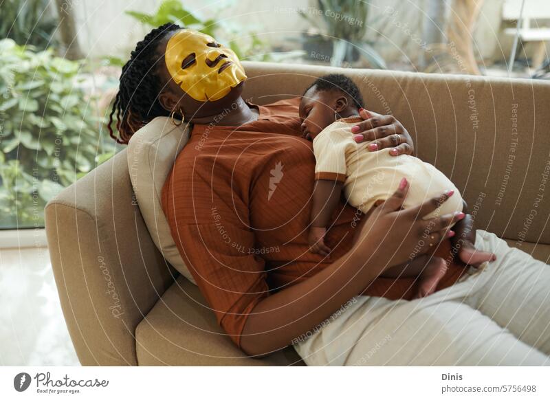 Black woman with moisturizing face mask on sleeping with her newborn baby asleep tired mother Baby beauty infant girl calm motherhood little child care
