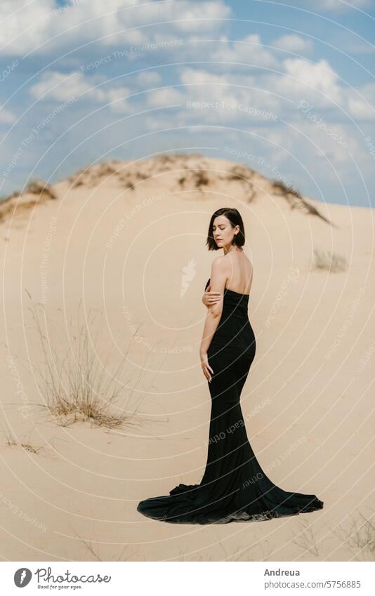 girl in a black long dress in a sandy desert alone away from home blue clouds day diversity evening evolve extreme hair hard-to-reach high hot make-up model