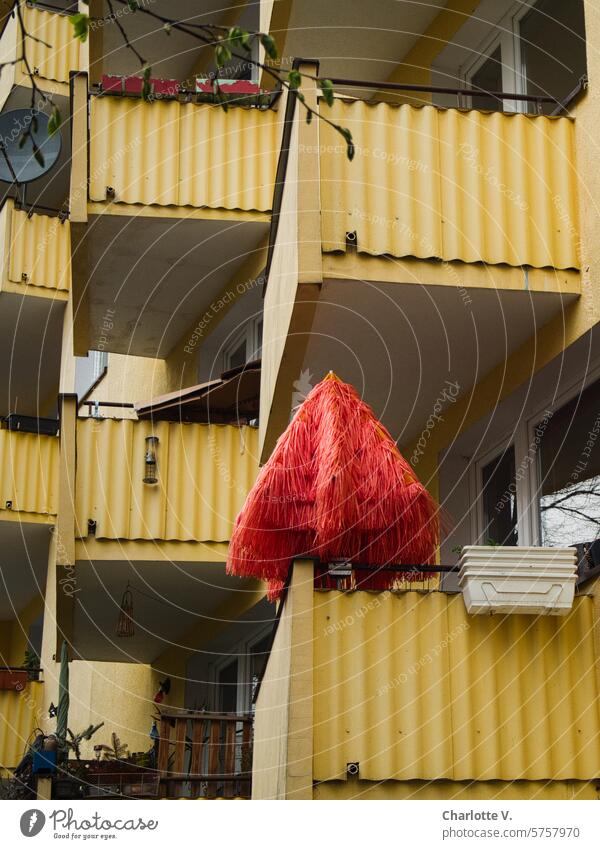 Roter Sonnenschirm auf einem von vielen gelben Balkonen Schirm roter Schirm Hausfassade geschlossener Sonnenschirm urban Gebäude Blumenkästen leere Blumenkästen