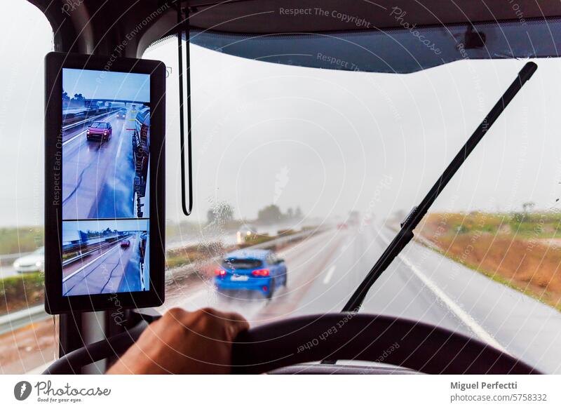 View from the driver's seat of a truck on a highway with poor visibility due to heavy rain, with the windshield wipers operating. inside traffic weather