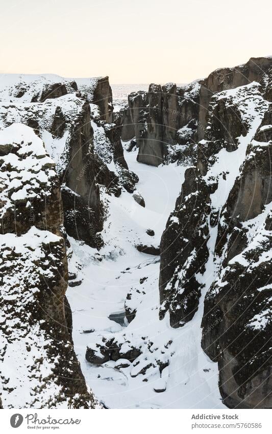 A winter view of the Fjadrargljufur Canyon in Iceland, with snow accentuating the rugged contours of the ancient cliffs canyon landscape nature snow-covered