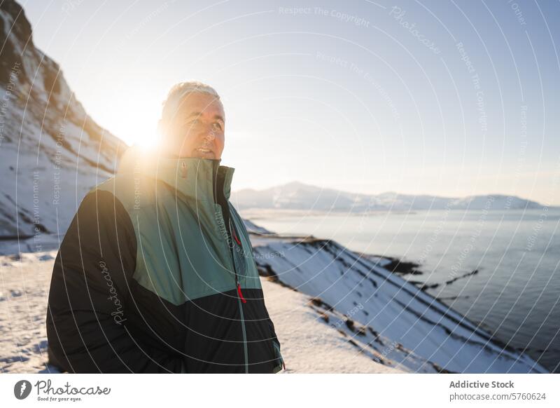 A traveler in a warm coat savors the tranquil moments of a sunlit winter day, overlooking the snowy coastline of Iceland Icelandic sunlight serene cold outdoors
