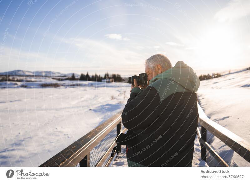 A photographer stands on a bridge in Iceland, camera in hand, capturing the stunning winter scenery bathed in the soft glow of the sun snow sunlight capture
